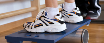 Füsse in Turnschuhen balancieren auf Brett Füsse in Turnschuhen balancieren auf Brett
